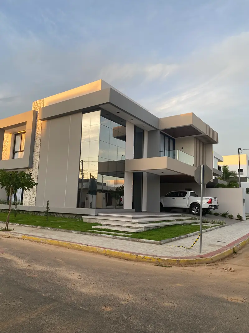Foto do sobrado construído, com pele de vidro e garagem coberta