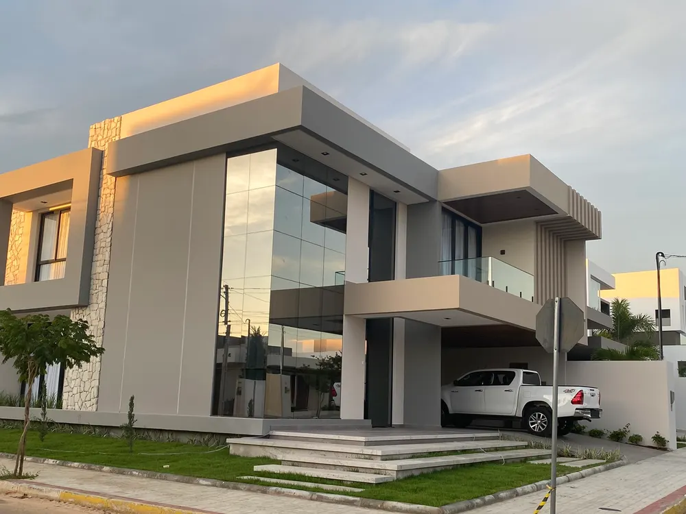 Foto do sobrado construído, com pele de vidro e garagem coberta