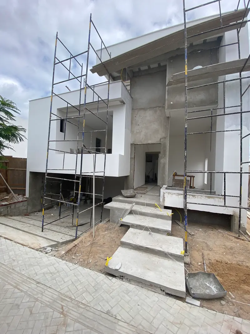 Fachada de sobrado recebendo argamassa, com volumes em balanço, durante a execução