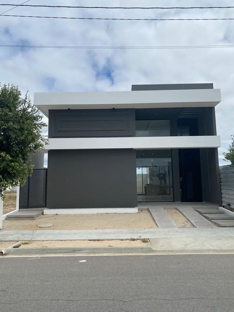 Foto da casa construída, com volume escuro e marquise branca